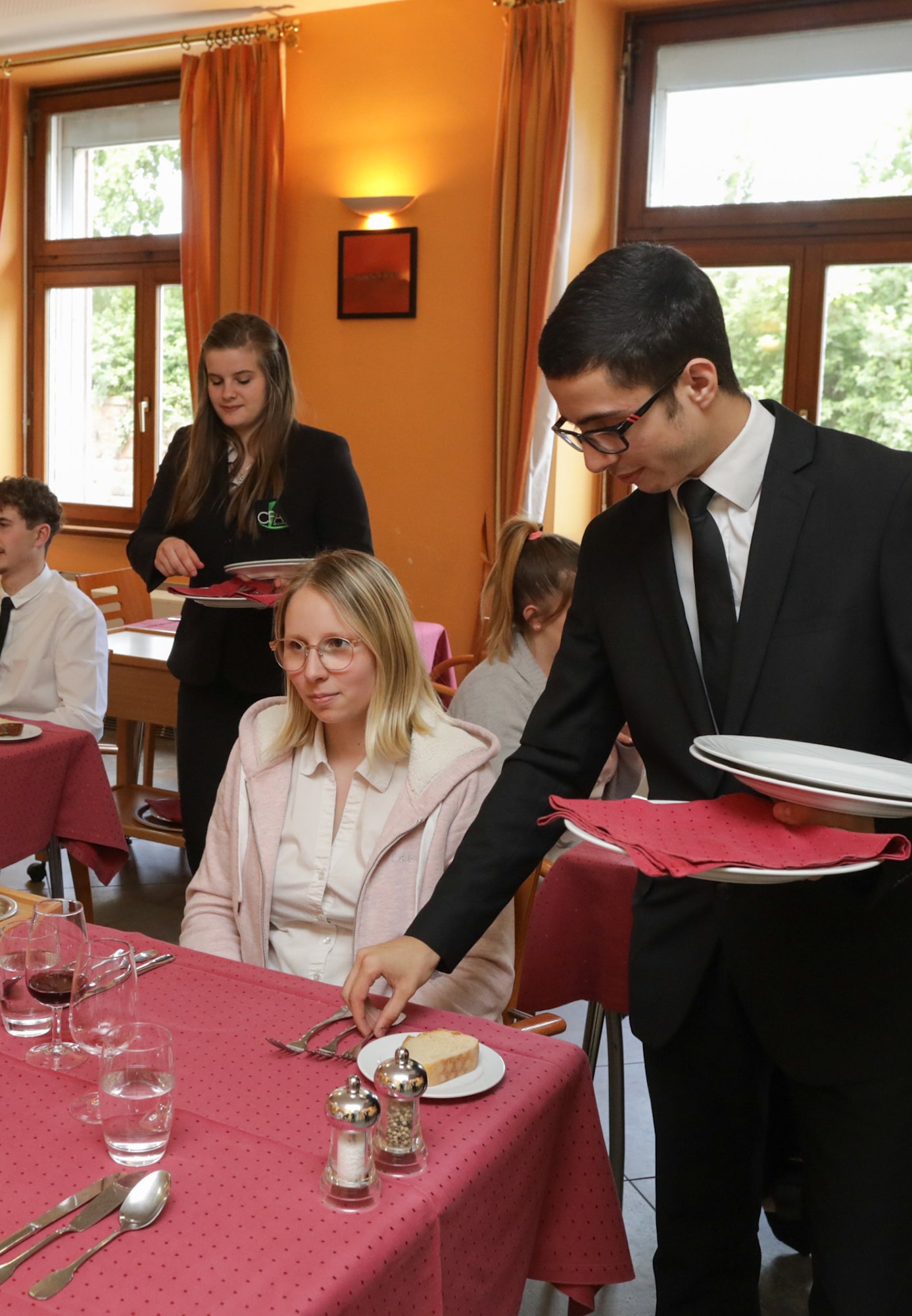 Service à table par un apprenti en tenue, devant une cliente