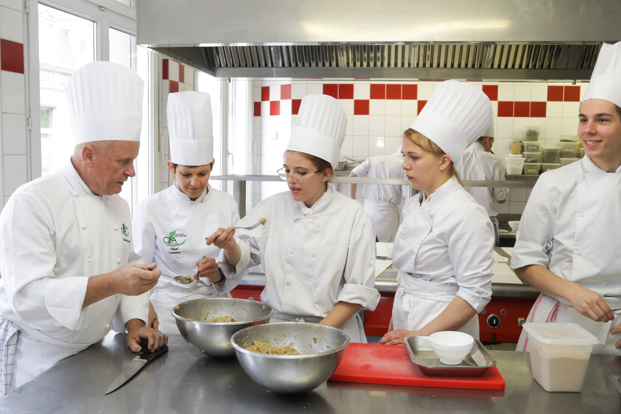 Des apprentis en veste blanche préparent leurs bases en cuisine