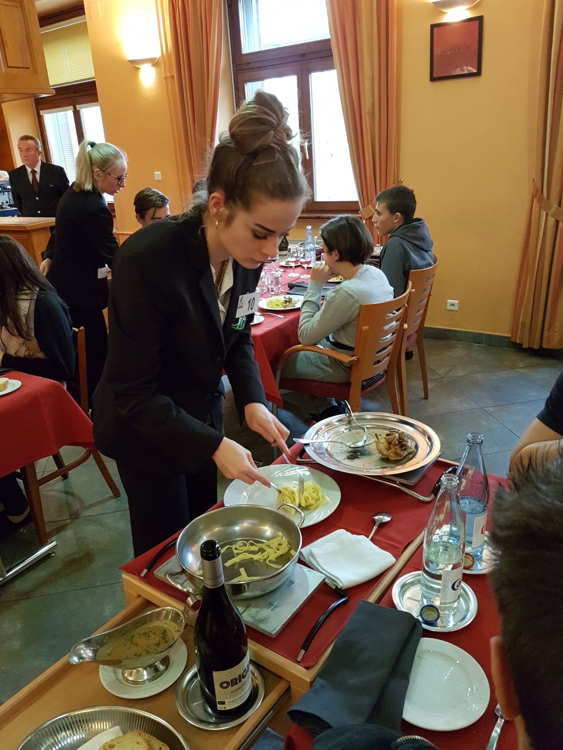 Une apprentie de salle dresse une table du restaurant d’application