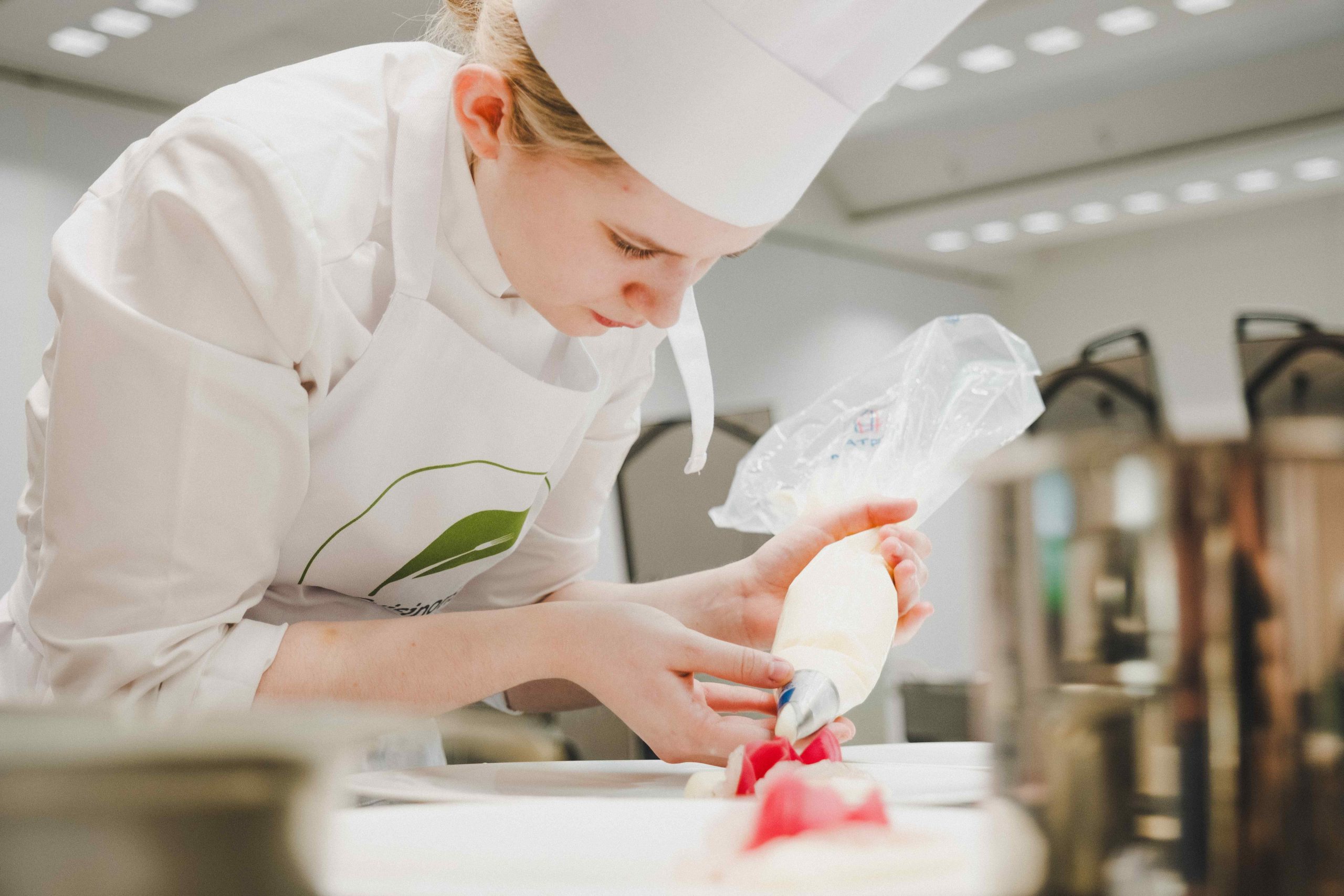 Une apprentie pâtissière dresse un dessert à l’assiette